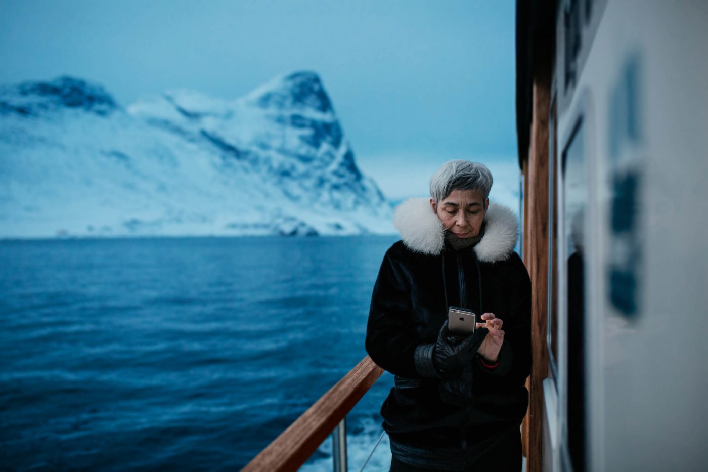 A greenlandic woman with her phone on a tour with Arctic Boat Charter near Nuuk in Greenland. Photo by Rebecca Gustafsson