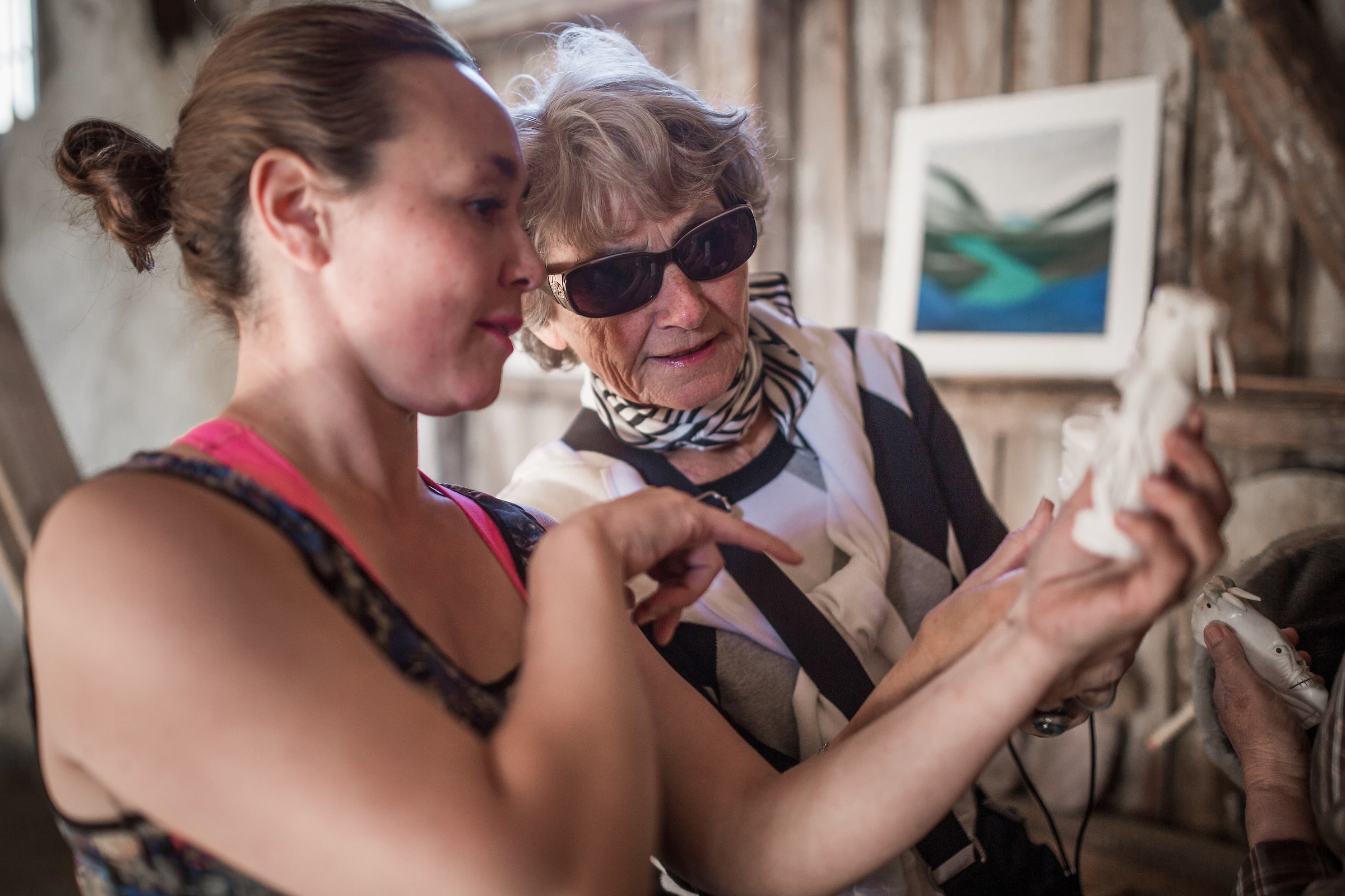 Kattie from Hotel Narsaq telling a guest about a tupilak bone carving from Narsaq in South Greenland. Photo by Mads Pihl - Visit Greenland