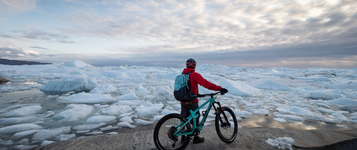 Chris Winter enjoying one of the most spectacular views you can get to by mountain bike. Ilulissat Icefjord, Ilulissat, North Greenland.Photo by Ben Haggar - Visit Greenland