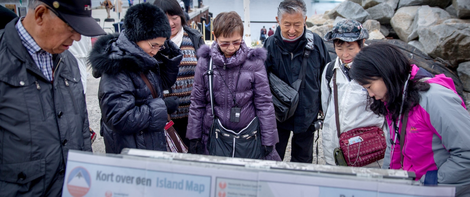 Cruise guests in Nanortalik in South Greenland studying a map of town