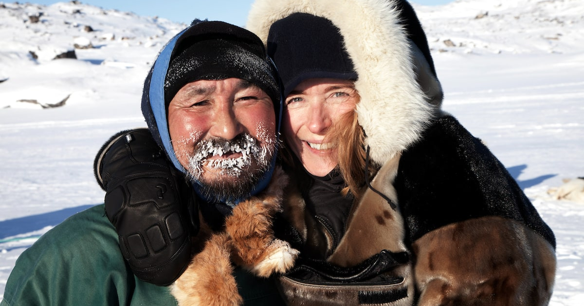 A dog sled driver and his happy passenger enjoying a day of dog sledding in Ilulissat in Greenland