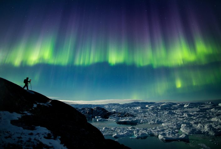 A photographer on a photo tour in North Greenland captures the perfect nighttime shot of northern lights, the starry night sky, and icebergs in the Ilulissat Icefjord. Photo by Paul Zizka