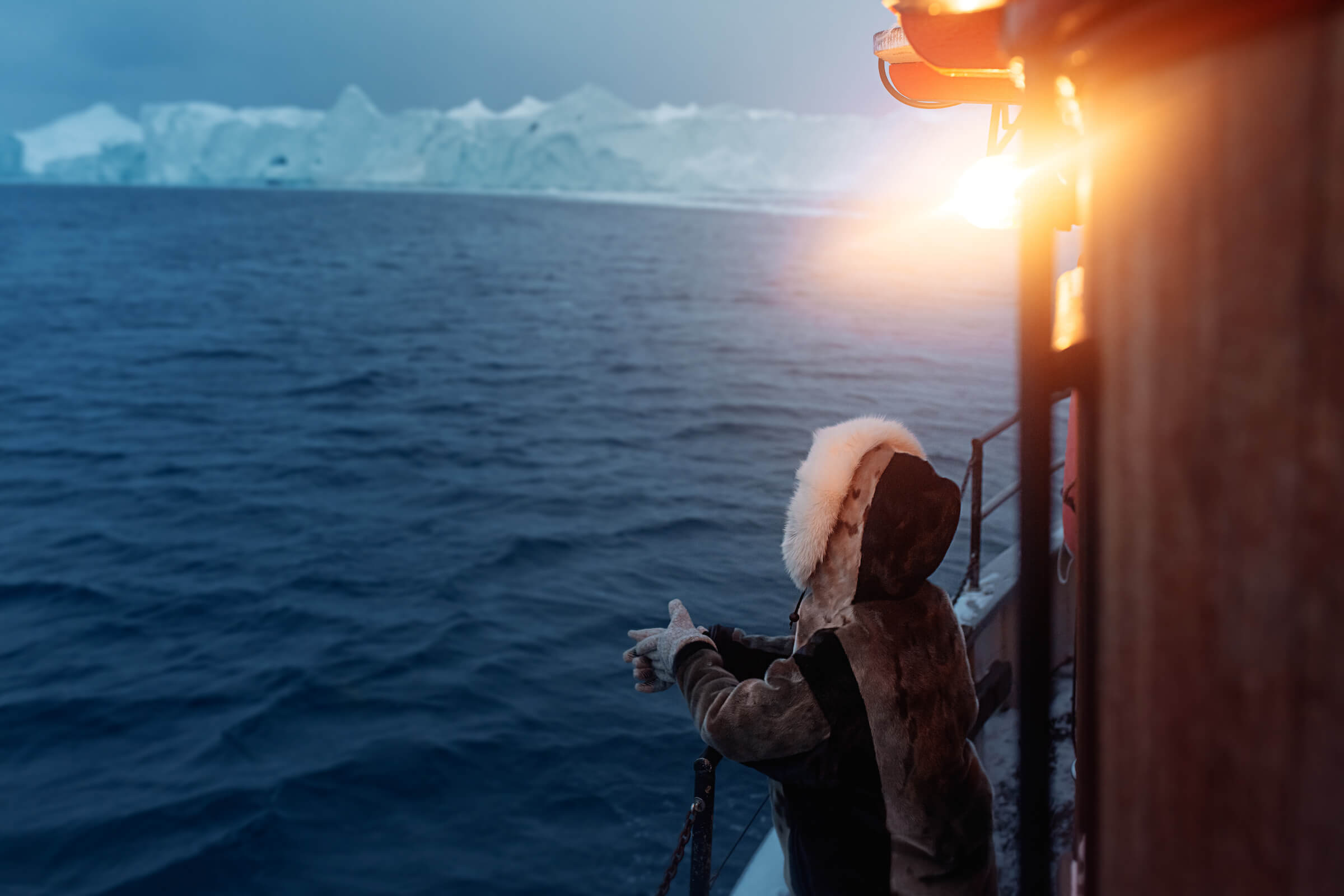Seal skin dressed tourist looking out over the icebergs of the Ilulissat icefjord in Greenland. Rebecca Gustafsson